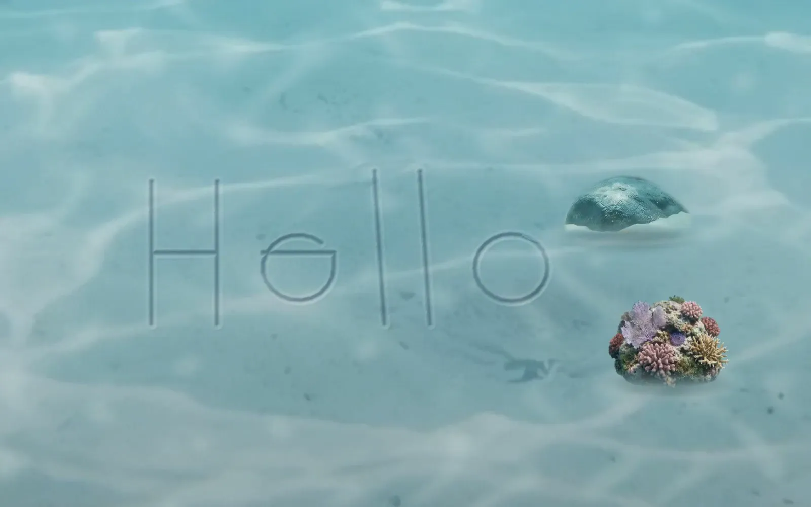 Hello, written in the sand with a finger, with two stones set beside it.